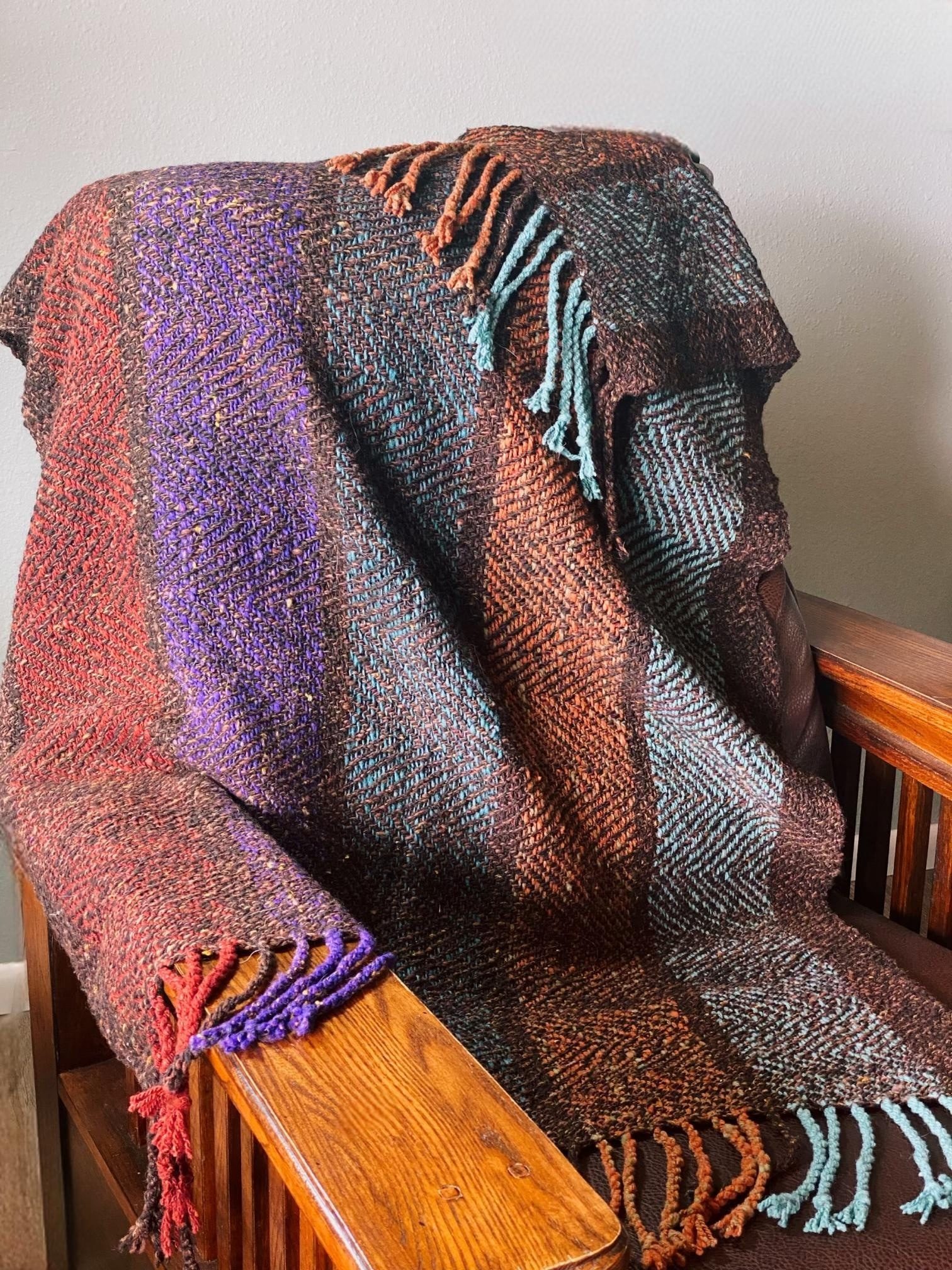 Herringbone weave handwoven throw blanket draped on a wooden bench